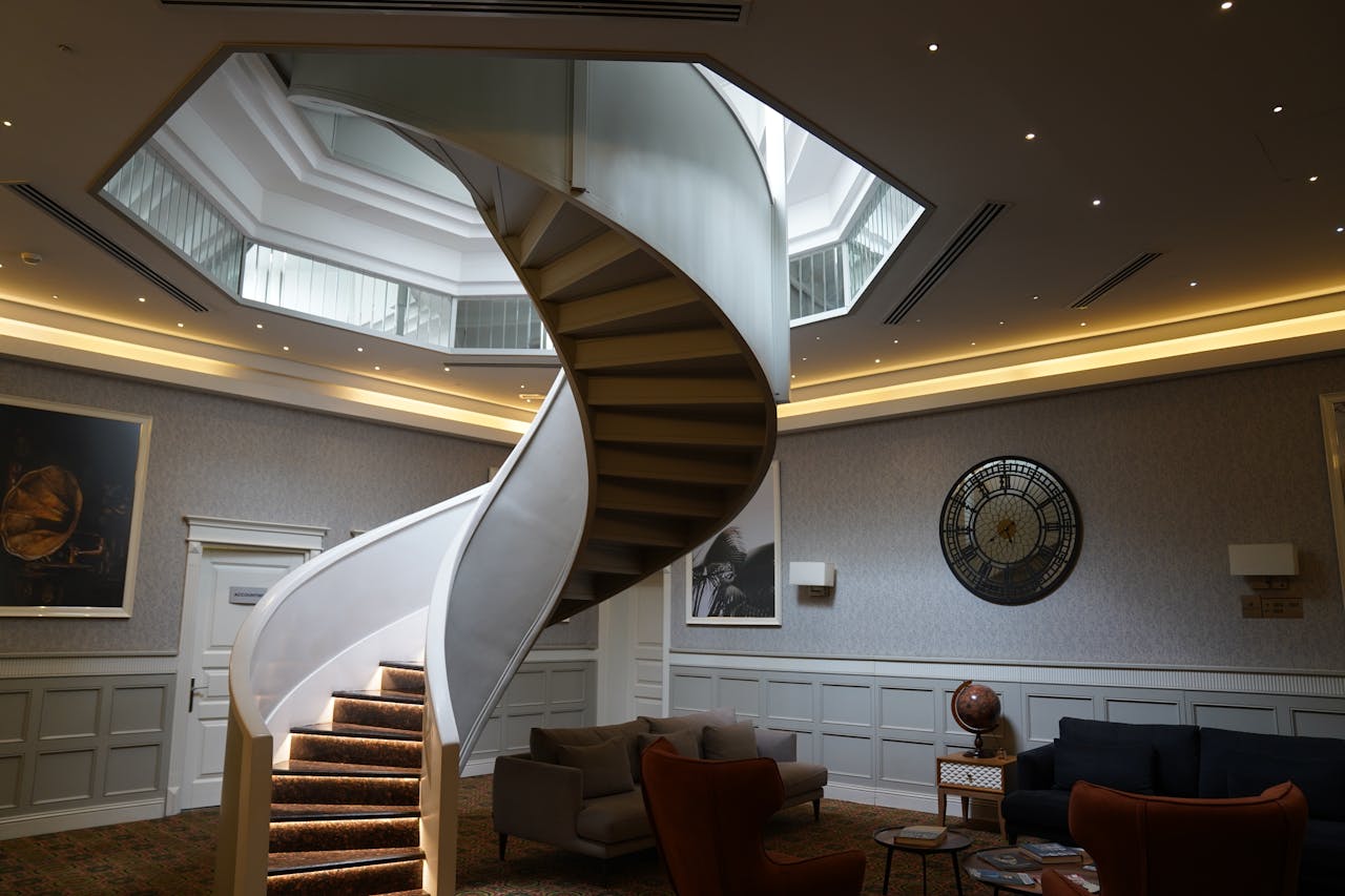 Stylish spiral staircase leading to skylight in a modern lounge with elegant decor.